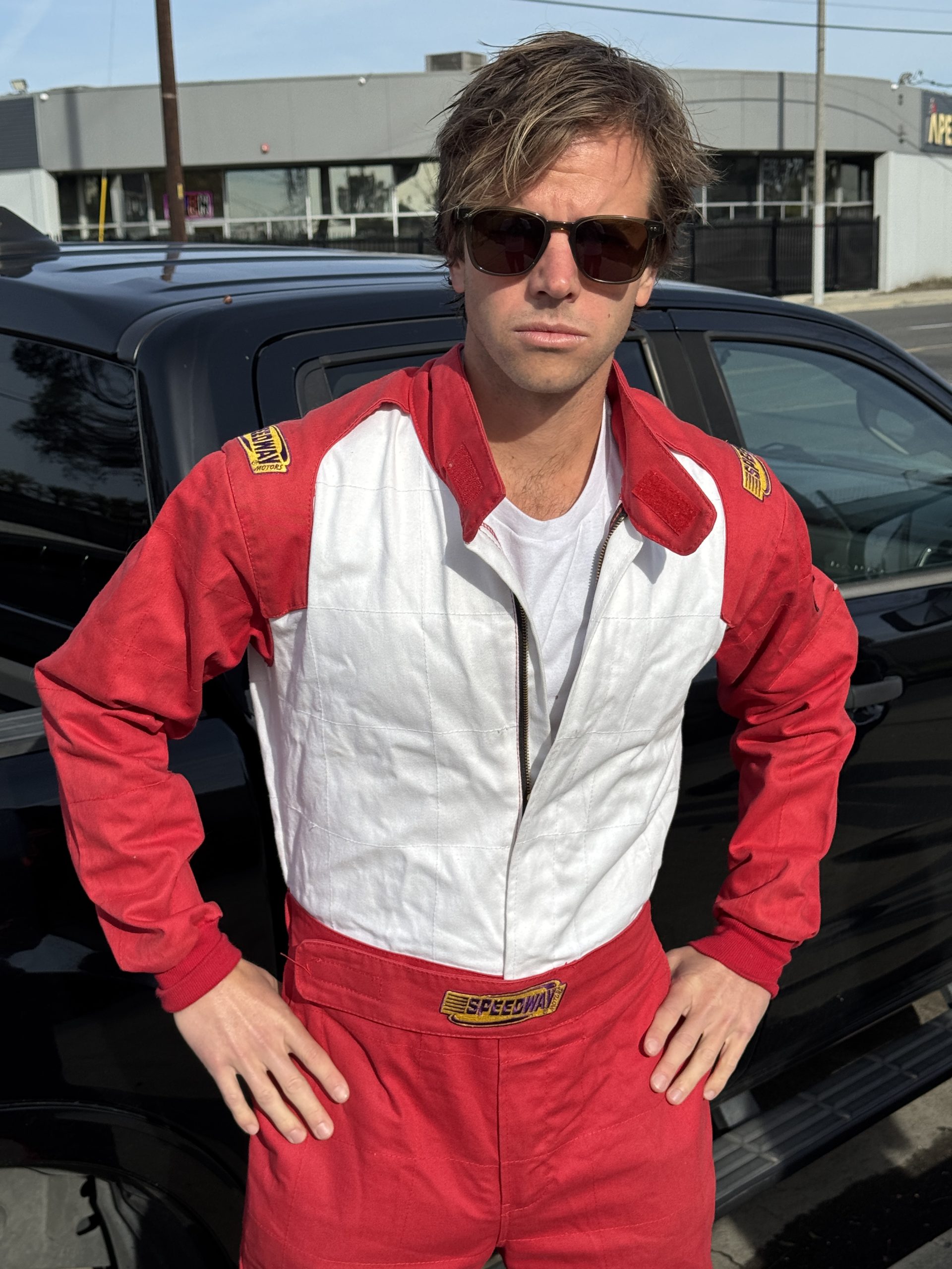 Chad Kroeger posing in a vintage red and white Speedway racing suit and sunglasses