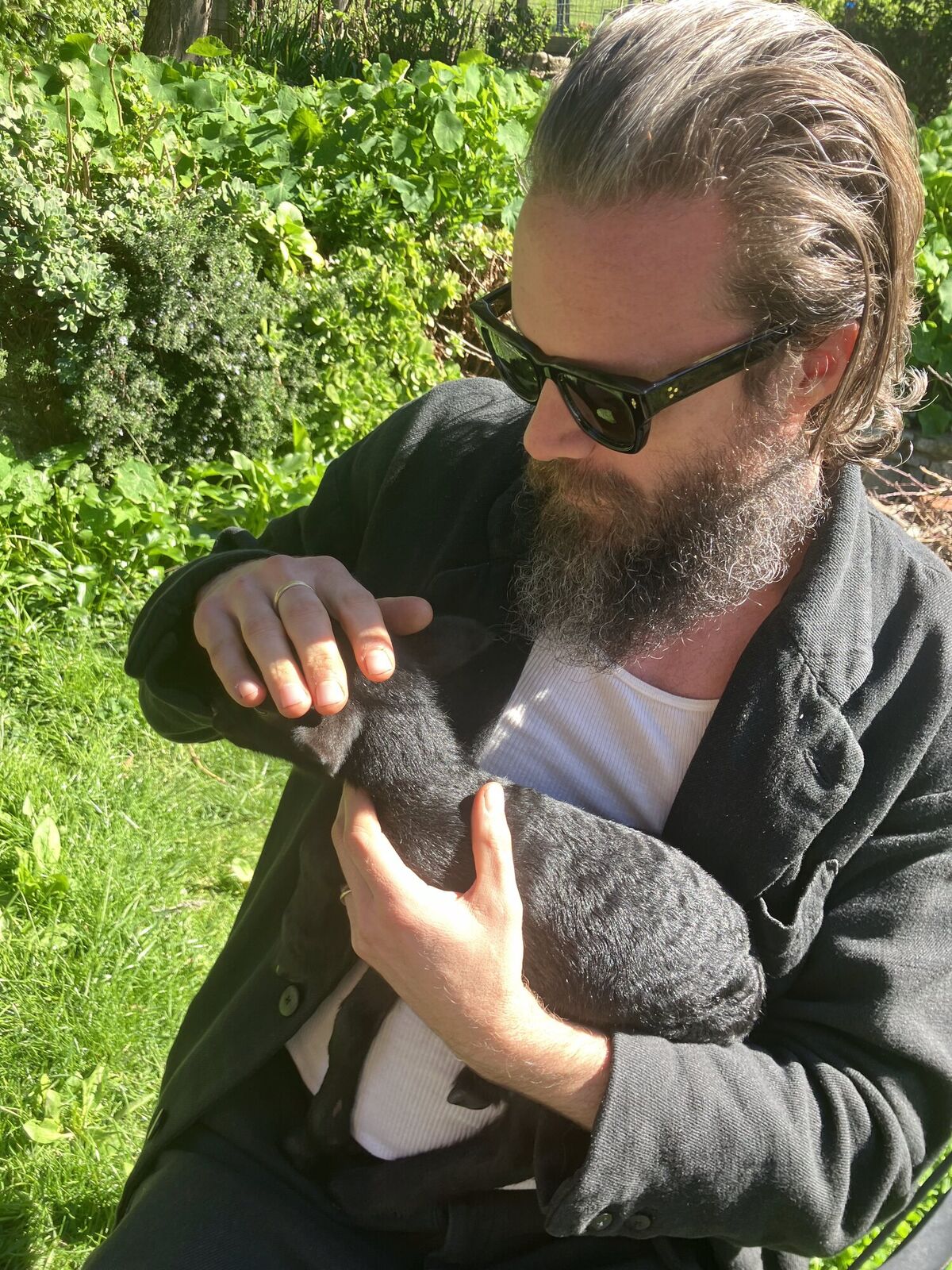 Father John Misty holding a lamb outdoors
