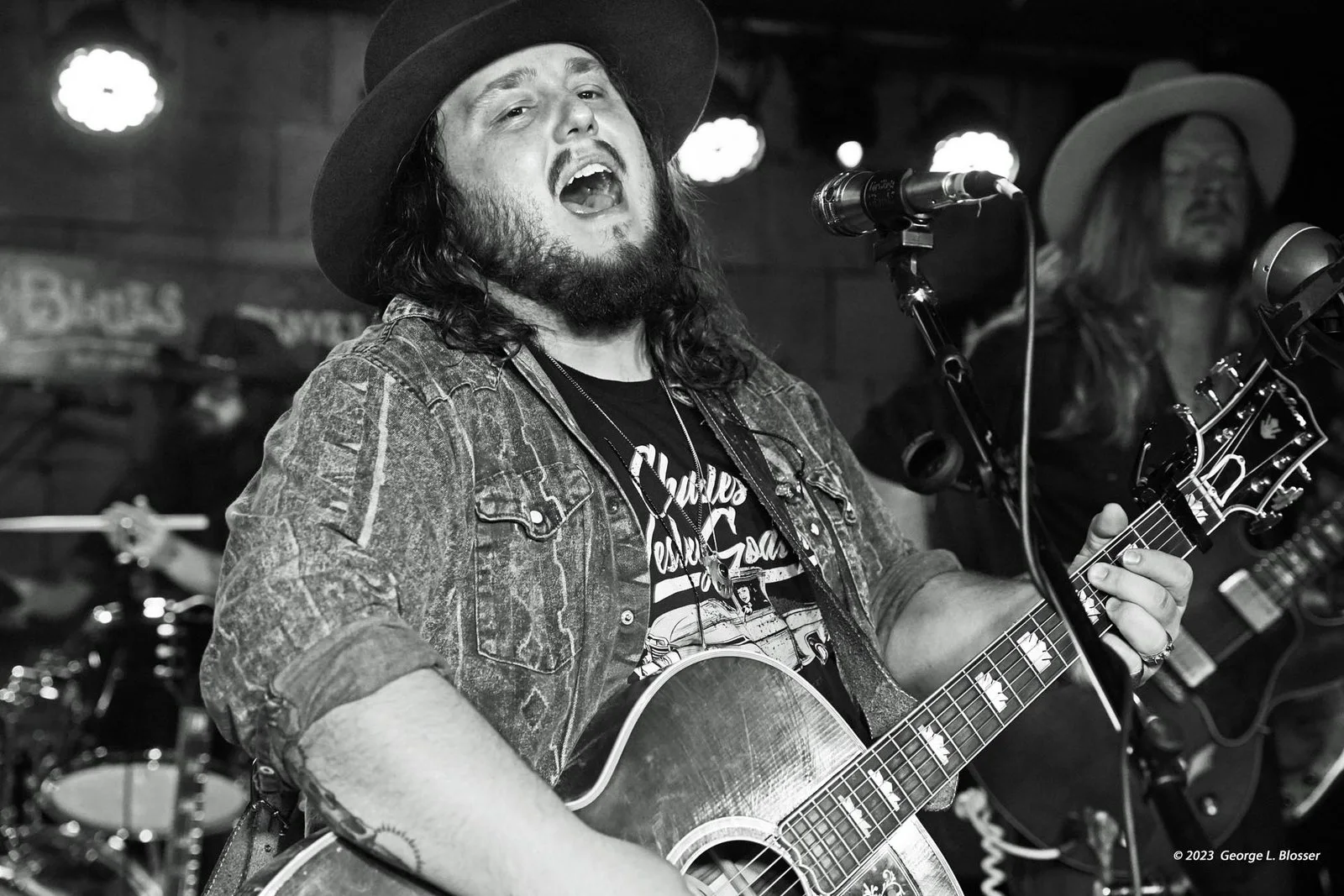 Tanner Usrey belts with an acoustic guitar, in black and white.