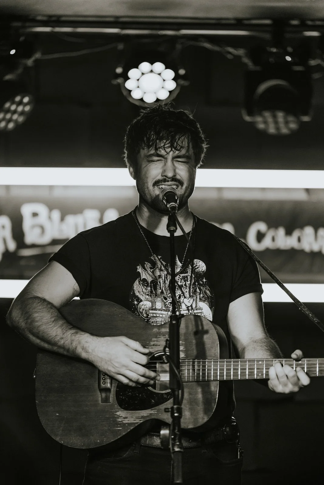 Wheelwright sings with eyes closed and an acoustic guitar under the stage lights.