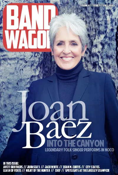 Joan Baez smiles in a navy blazer and dark turtleneck before a weathered tree trunk on a BandWagon cover.