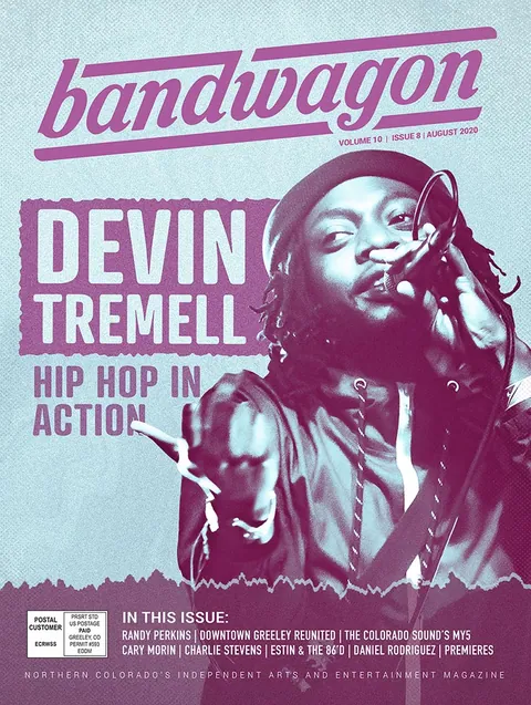 Devin Tremell performs into a microphone in a dark hat, one arm outstretched, in a duotone magenta and blue image.