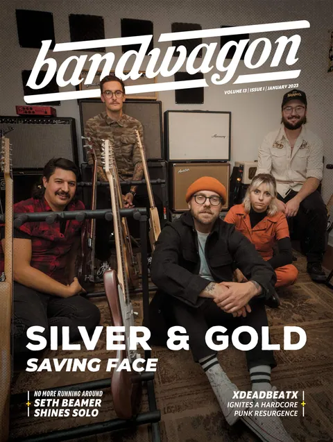 Silver & Gold, five members posing with guitars on stands and amplifiers in a room with acoustic foam panels.