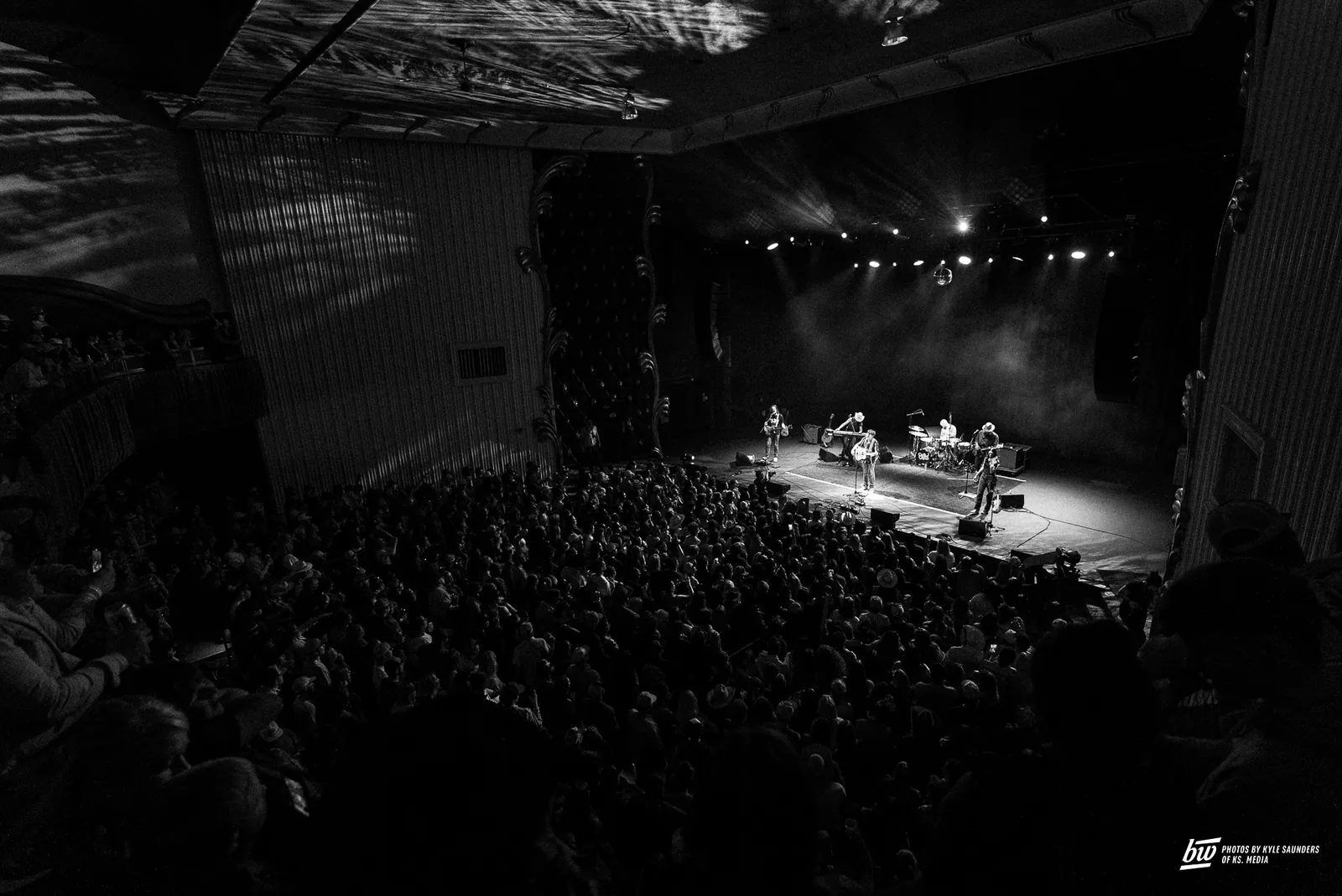 Wyatt Flores performs to a packed black-and-white crowd at The Lincoln, with guitars and drums under stage lights.