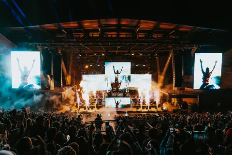 Shaq's Bass All Stars perform at Red Rocks with flames, large screens, and a crowd of fans holding up phones.