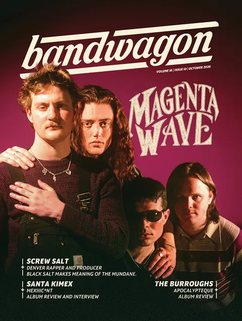 Magenta Wave poses for a group portrait against a magenta backdrop, four members in knitwear and striped shirts.